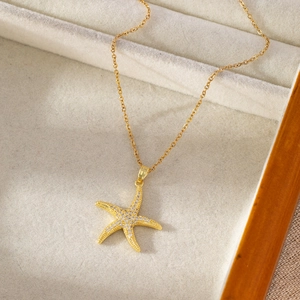 Bohemian gold starfish pendant necklace with micro-set zircons on a light velvet tray