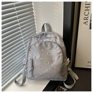 Detail view of the gray nylon backpack featuring a pink floral pattern and front pocket