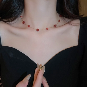 Detailed view of red agate beads on a gold-plated necklace worn on the collarbone