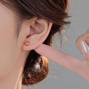 S999 silver stud earring with round orange zircon in a four-prong setting on ear