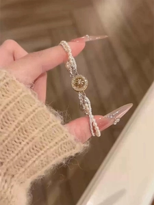 Detail of a French vintage pearl bracelet with a golden starburst pendant on a model wrist