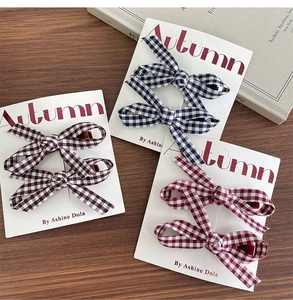 Detailed close-up of British style plaid bow hair clips in navy, brown, and wine red