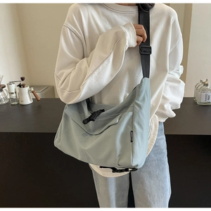 Detail of light blue messenger bag with black adjustable strap and unique knot zipper pull