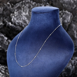 Silver bead-decorated chain necklace displayed on a navy blue velvet mannequin stand