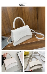 Detail of white crocodile pattern crossbody bag with braided handle and geometric flap