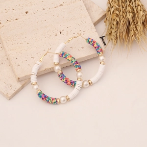 Bohemian rainbow polymer clay hoop earrings with pearls on a textured stone display