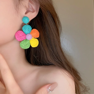 Close-up of colorful woven mesh flower earrings on model featuring a vibrant beach style