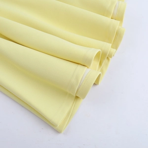 Gros plan sur la texture du tissu plissé jaune et les détails superposés de la robe