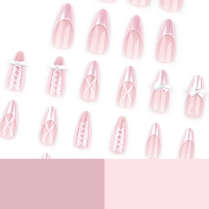 Pink press-on nails with pearl bow and white ribbon accents in almond shape