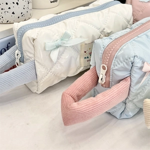 Close-up of quilted cosmetic bags with contrast zippers, velvet handles and bow details