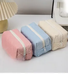 Detailed close-up of quilted corduroy cosmetic bags in pink, blue and off-white colors