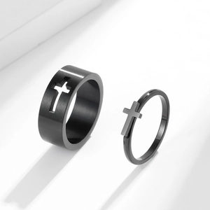 Brushed black stainless steel couple rings with hollow and 3D cross design on white background