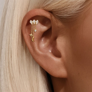 Macro shot of a gold earring with rhombus zircons and star-moon charms on a model