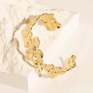 Detailed macro view of 18K gold-plated C-shaped open cuff bracelet with floral patterns