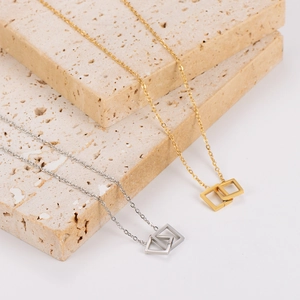 Elegant gold and silver geometric interlocking square pendant necklaces on stone display