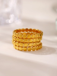Vue macro de quatre bagues carrées dorées empilées au design géométrique minimaliste chic