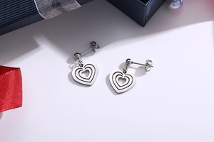 Detail of silver multilayered hollow heart earrings on blue gift box with pearls