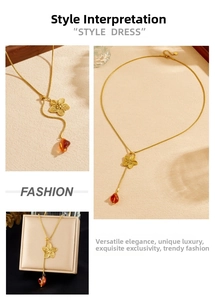 Detailed close-up of gold camellia pendant with amber resin bead on snake chain