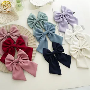 Flat lay of elegant large satin bow hair clips with long ribbons in multiple pastel colors