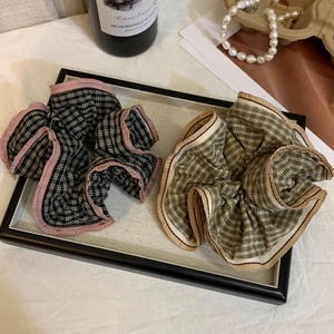 Detail of vintage plaid hair scrunchies in pink and brown on a black decorative tray