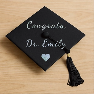 Macro shot of silver glitter calligraphy on a black graduation cap with silk tassel