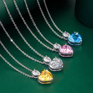 Gros plan de quatre pendentifs moissanite en forme de cœur bleu, rose, blanc et jaune