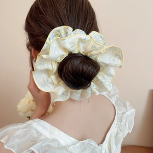 Detail of floral lace scrunchie in cream and yellow on a professional bun hairstyle