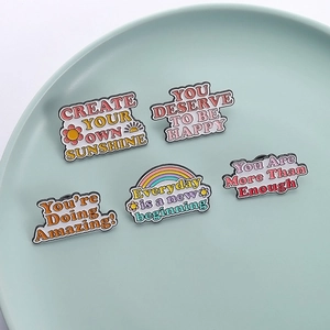 Detail shot of five colorful enamel pins with motivational quotes on a ceramic tray