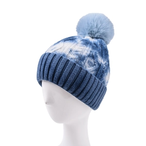 Detail of blue tie-dye knit beanie featuring a fluffy pompom and thick jacquard texture