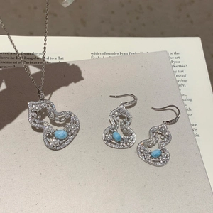 Detail of light blue stone jewelry set with pearls and zircons on open book background