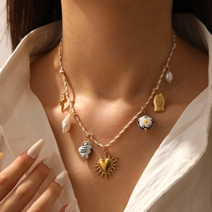 Detail of colorful charm necklace featuring gold heart, ceramic fish, and shell charms