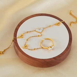 Gold stainless steel heart bracelet and ring set with mother of pearl on silk background
