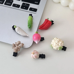 Détail de 7 pinces à cheveux légumes réalistes, ail et brocoli, sur une surface blanche
