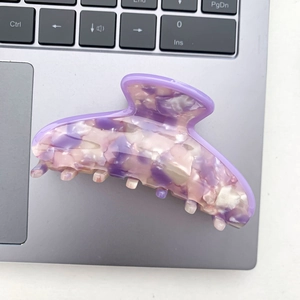 Detail of purple marble pattern acetate hair claw clip on a laptop keyboard