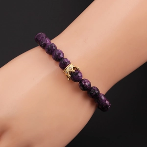 Detailed view of purple natural stone beads and a gold crown charm with sparkling crystals