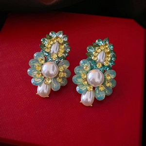 Détail des boucles d'oreilles fleurs avec perles et opales bleues sur écrin rouge