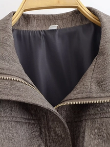 Close-up of brown herringbone fabric and metal zipper detail on bomber jacket