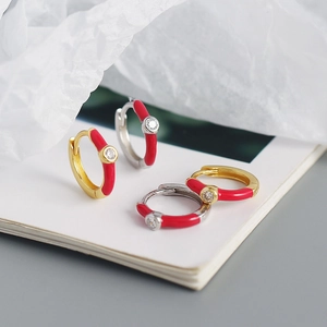Macro shot of gold and silver S925 earrings with red enamel coating and zircon stones