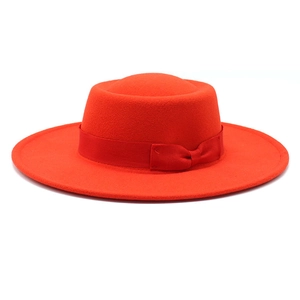 Detail of red wool felt boater hat with flat brim and elegant ribbon bow decoration