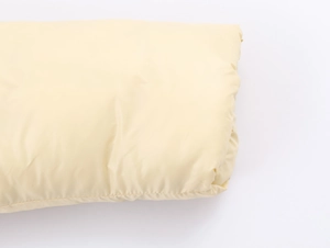 Detailed close-up of light yellow padded jacket with fine stitching and fluffy padding