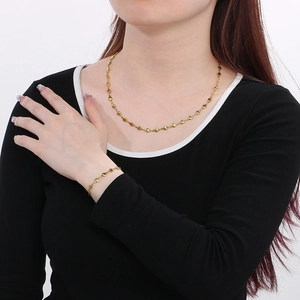 Ensemble collier et bracelet cœur en acier inoxydable doré porté par un mannequin