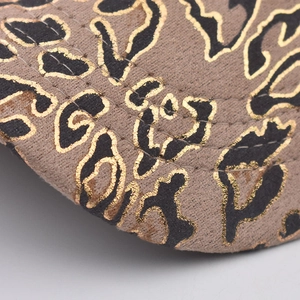 Detailed close-up of leopard print fabric with gold foil outlines and fine double stitching