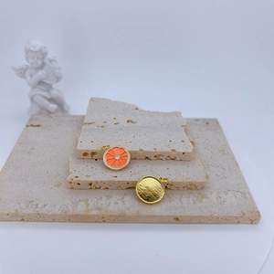 Detailed macro view of gold-plated lemon slice and textured round charm pendants