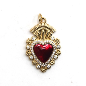Macro detail of a golden heart pendant with red enamel and sparkling crystal accents