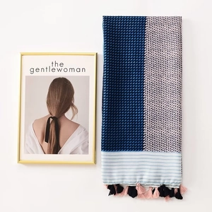 Detail of blue geometric scarf with light blue stripes and pink fringe tassels