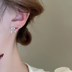 Macro detail of silver heart earrings with pink zircon and red rectangle gemstone