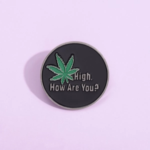 Round black enamel brooch with green leaf and High How Are You text inscription
