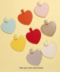 Flat lay of heart-shaped portable makeup mirrors in 8 colors with leather texture