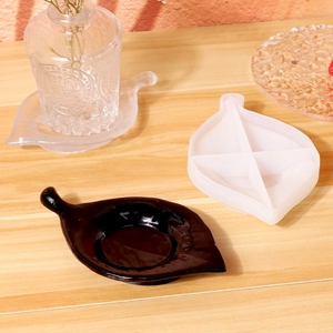 Moule en silicone en forme de feuille et coupelle en résine noire sur table en bois