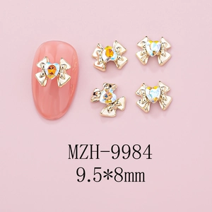 Macro detail of alloy bowknot nail charms with heart rhinestone, size 9.5x8mm on pink base